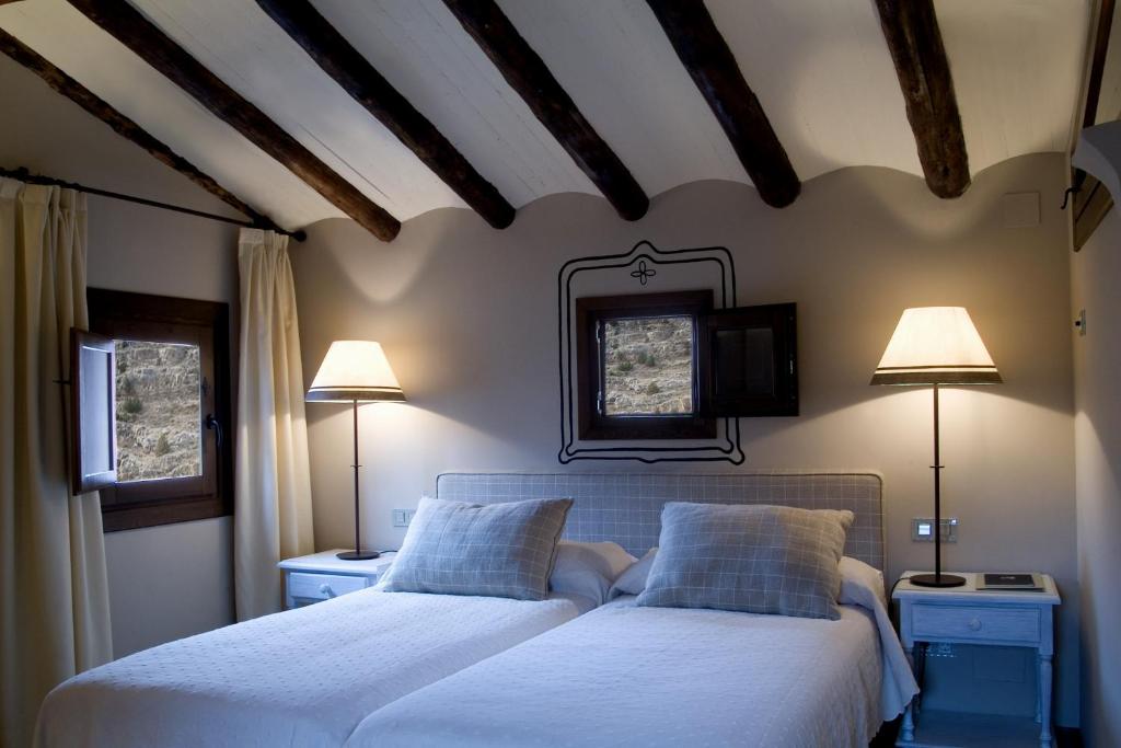 dwa łóżka w sypialni z dwoma lampami i telewizorem w obiekcie La Casa del tío Americano w Albarracín