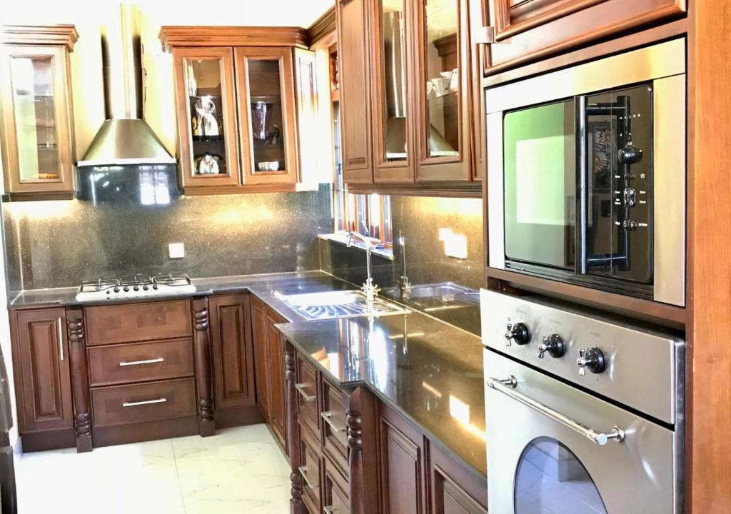 a kitchen with wooden cabinets and stainless steel appliances at Ama Villa Negombo in Negombo