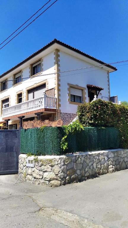 ein weißes Haus mit einer Steinmauer davor in der Unterkunft VILLA Mamuki - habitación doble in Prezanes