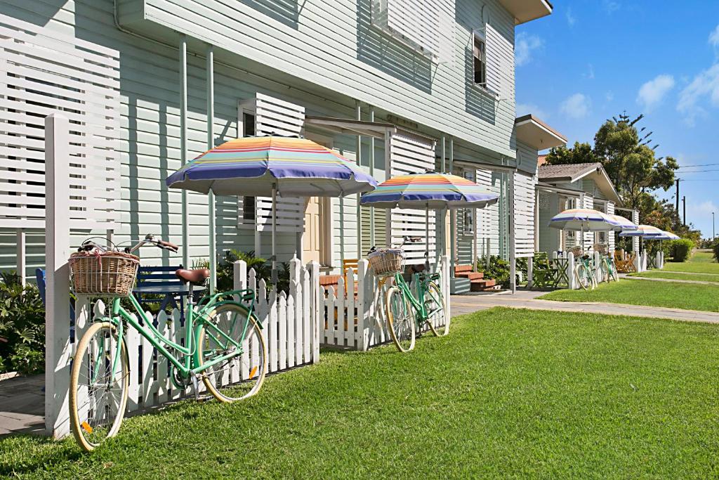 La Costa Beachside Motel في غولد كوست: مجموعة من الدراجات متوقفة بجوار منزل مع مظلات