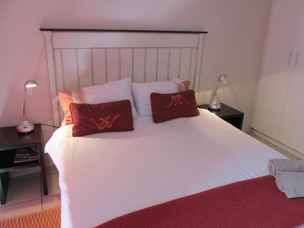 a bedroom with a white bed with red pillows at Point Village Accommodation - Santos 11 in Mossel Bay