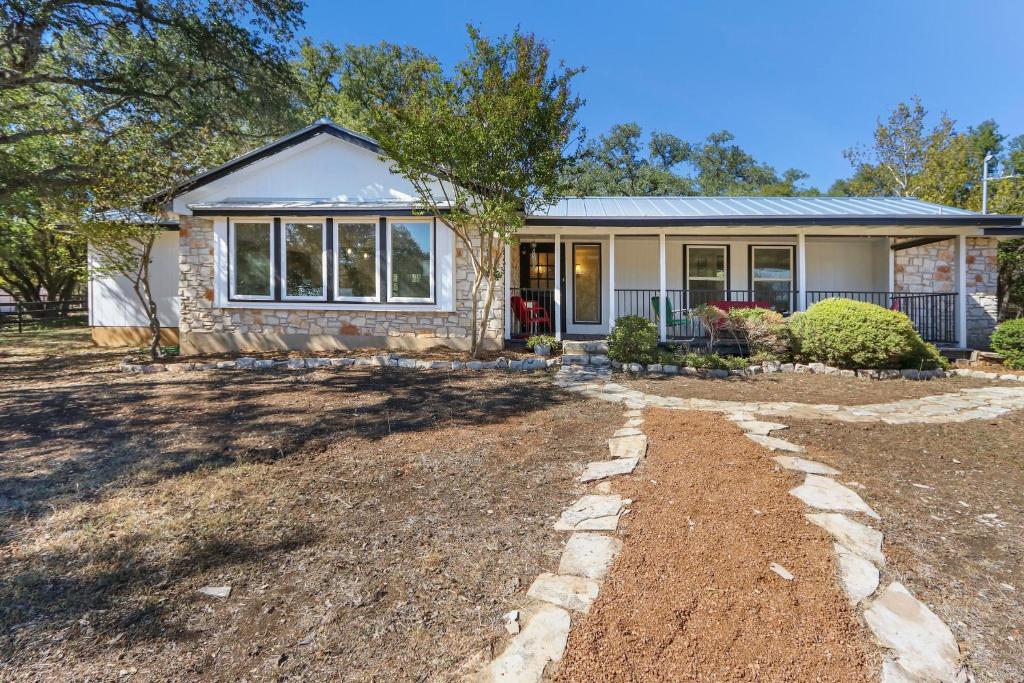 a house with a gravel driveway in front of it at Red Donkey Cottage in Wimberley
