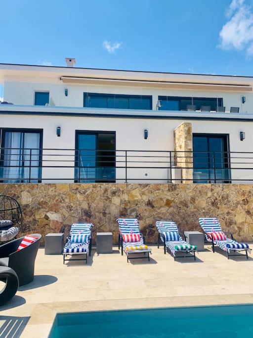 un groupe de chaises assises devant un bâtiment dans l'établissement Villa vue mer et piscine privée, à Sari-Solenzara