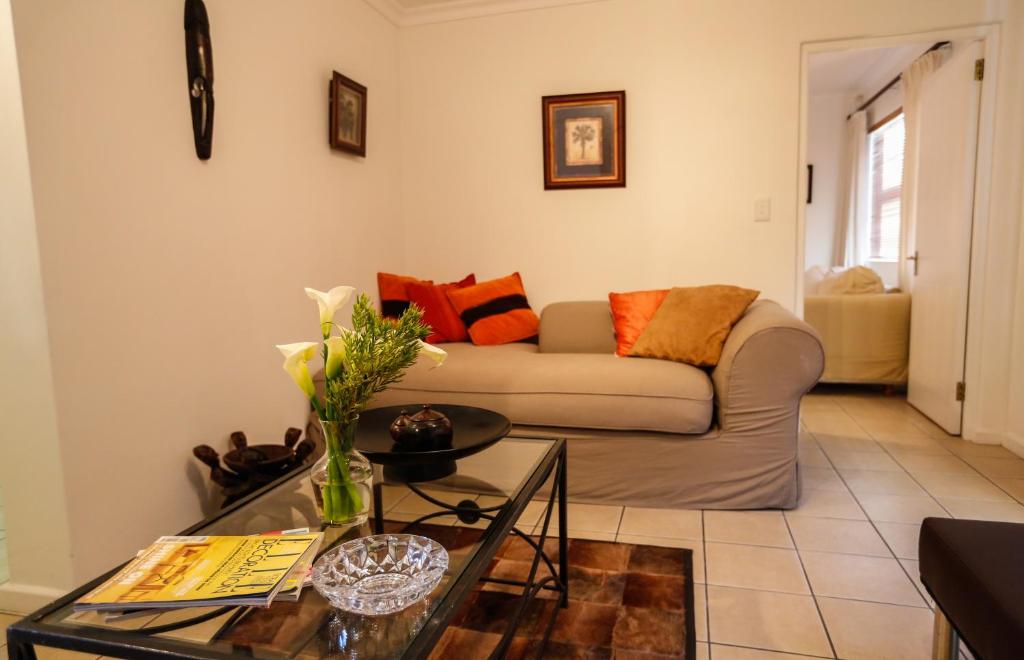 a living room with a couch and a table at Secret Garden Guesthouse in Bloubergstrand