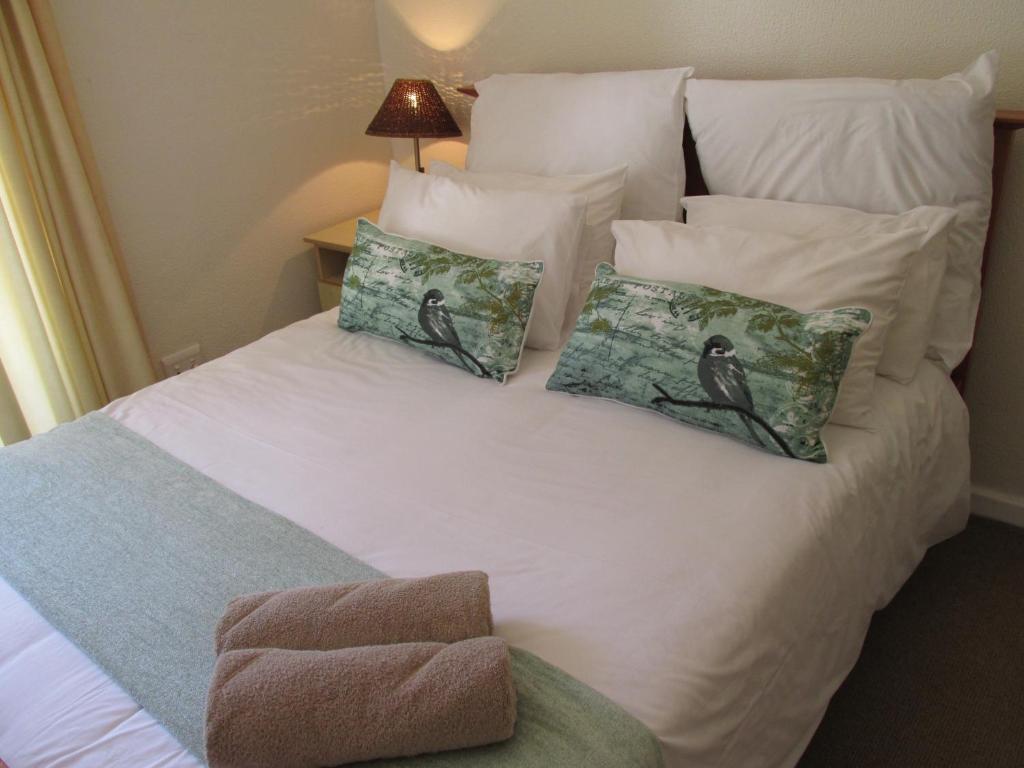 uma grande cama branca com almofadas em Point Village Accommodation - Santos 57 em Mossel Bay