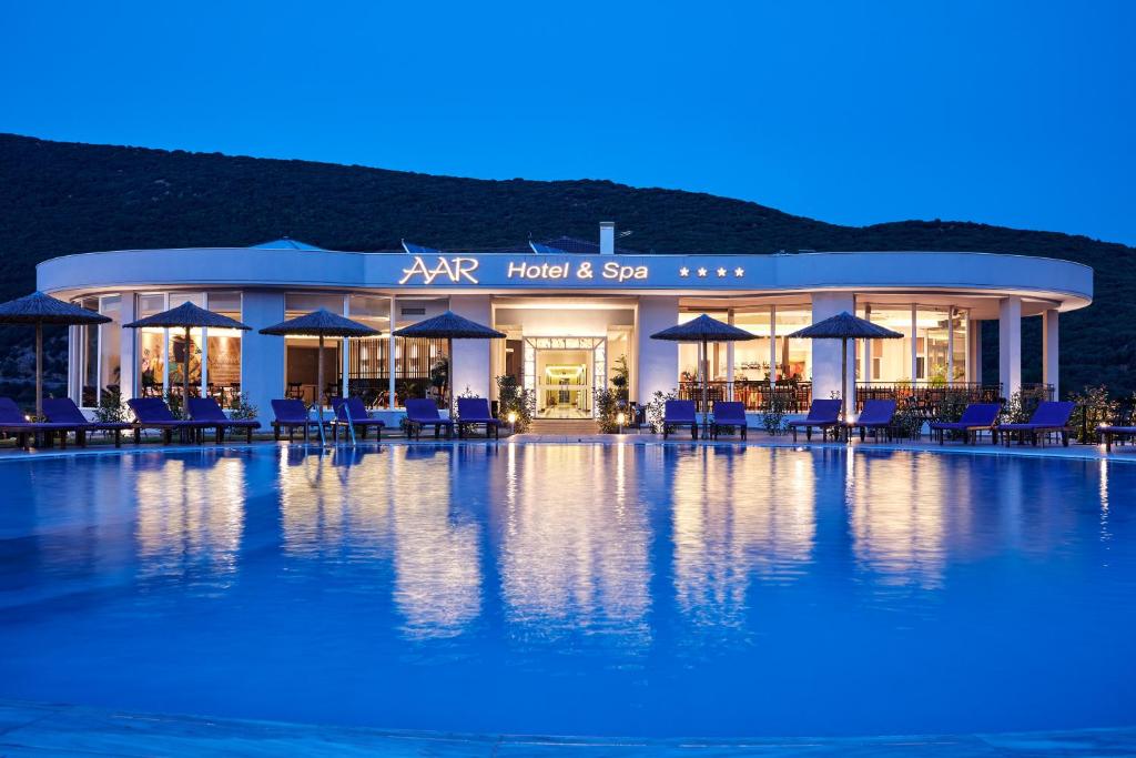 uma piscina com cadeiras e guarda-sóis em frente a um hotel em Aar Hotel & Spa Ioannina em Ioannina