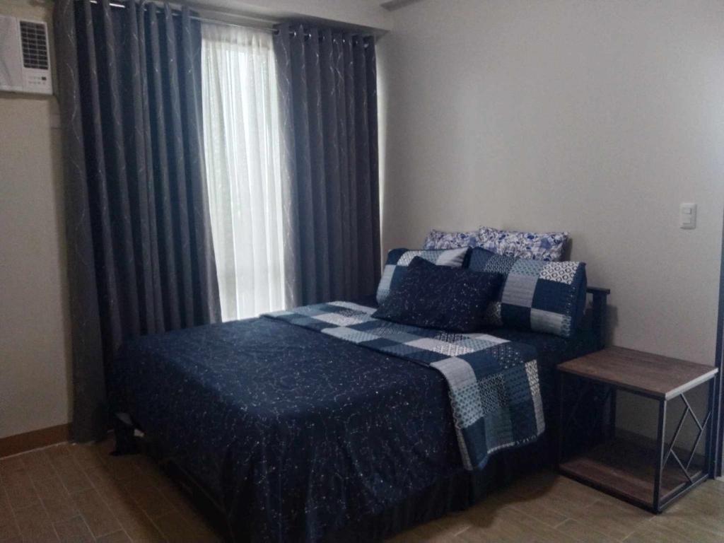 a bedroom with a bed and a window with curtains at Cozy, spacious and well lighted condo in Iloilo City