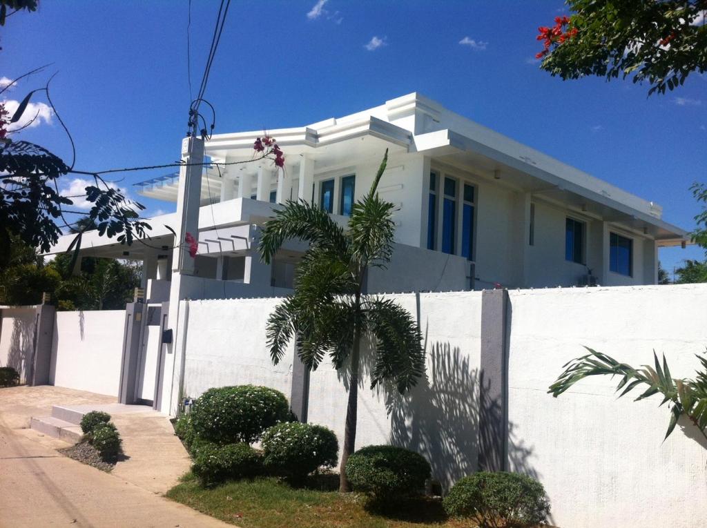 a white house with a white fence and a palm tree at Anavada Apartment - Davao City in Davao City