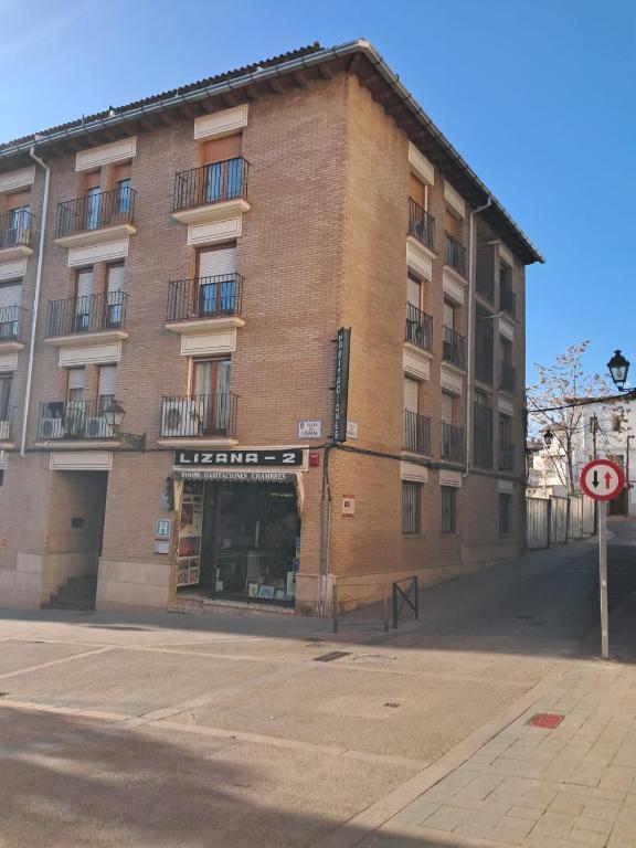 Un gran edificio de ladrillo al costado de una calle. en Hostal Lizana 2, en Huesca