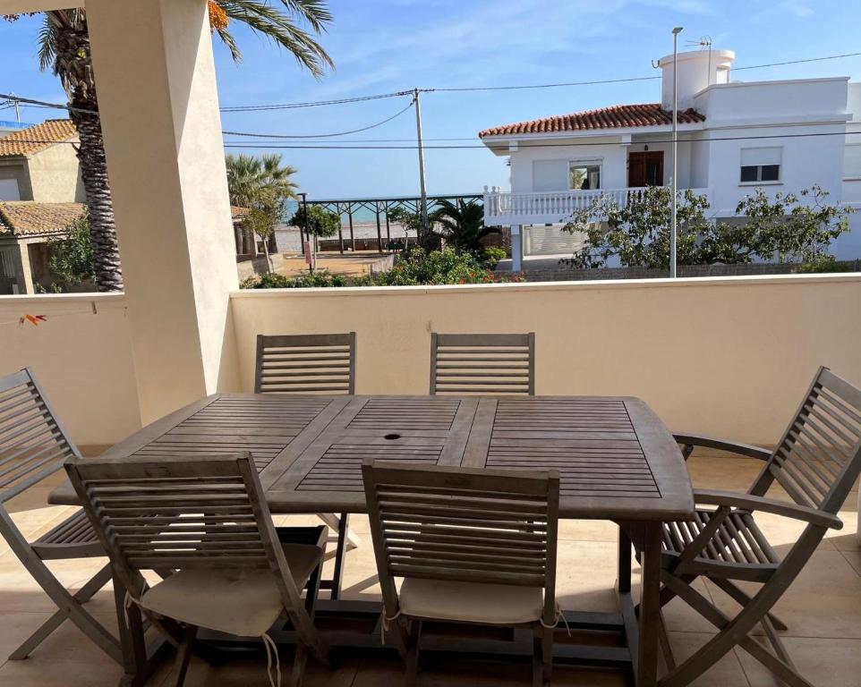 Una mesa y sillas de madera en un balcón. en La casa del viajero junto al mar, en Barrio-Mar