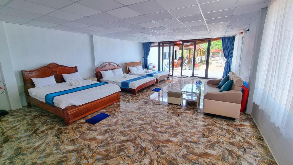 a hotel room with two beds and a couch and chairs at Vung Bau Resort in Phú Quốc