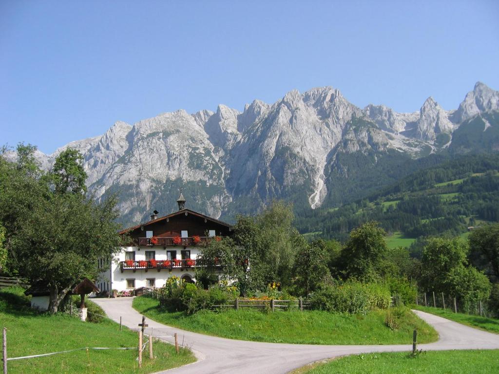 ein Haus auf einer Straße mit Bergen im Hintergrund in der Unterkunft Bio-Bauernhof Rettenbachgut in Werfen