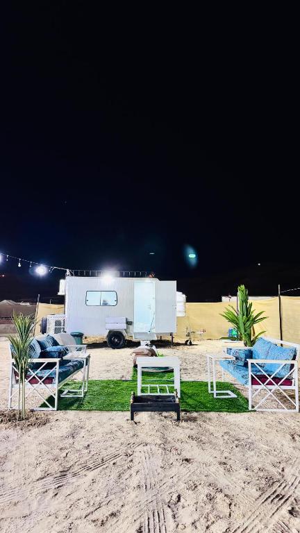 una playa con sillas, una mesa y un remolque en Big bear camping, en Nafīr