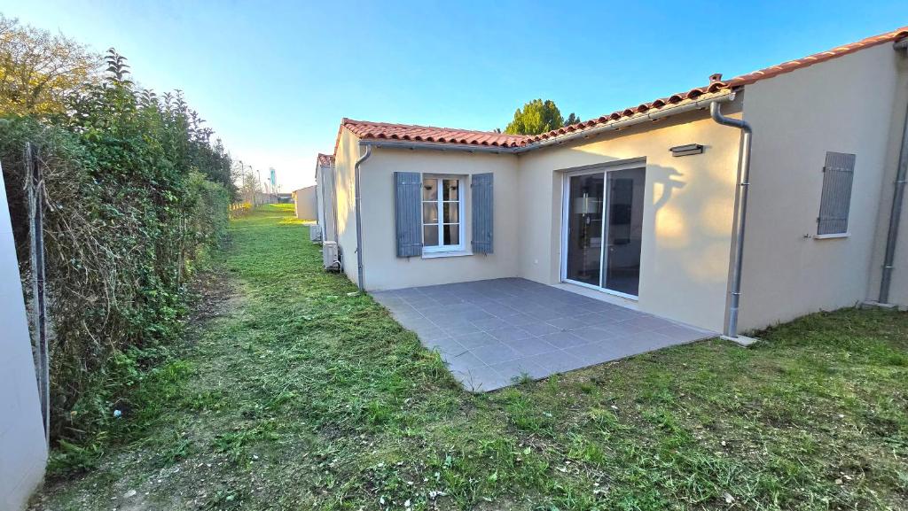 una pequeña casa blanca con una puerta en el patio en Résidence Au Cœur de Soi, en Jonzac