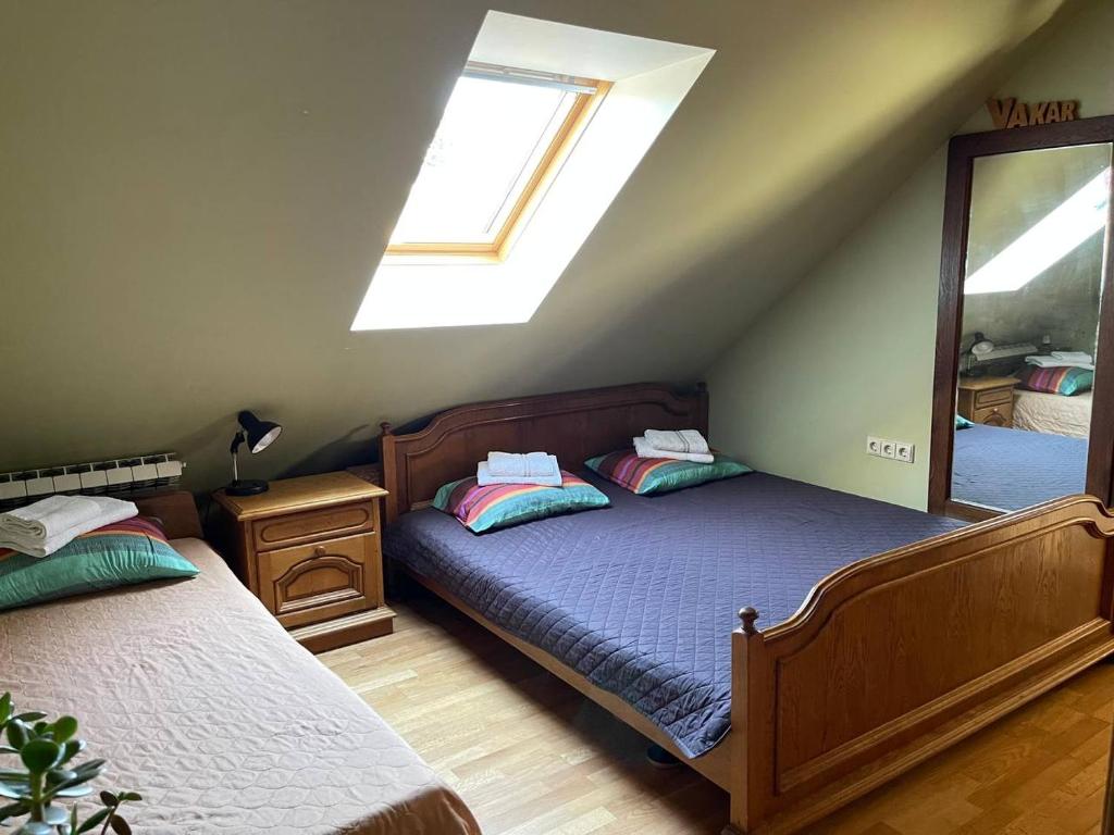 a attic bedroom with two beds and a mirror at Gallery Guest Rooms in Kernavė