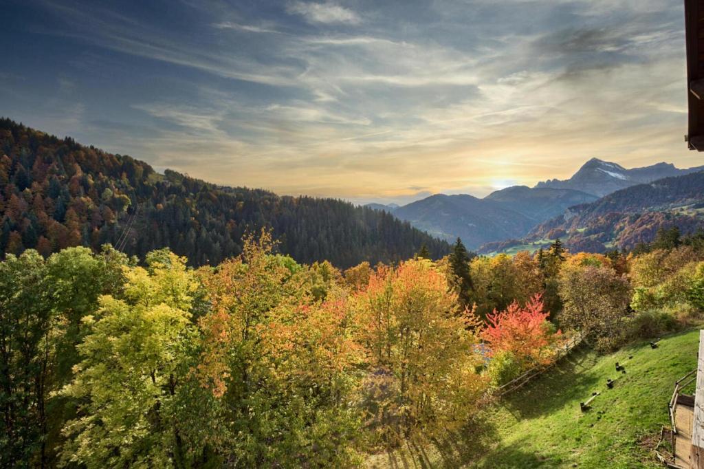 une vue sur une vallée avec des arbres et des montagnes dans l'établissement Résidence Les Balcons Du Charvin - Appartement de charme avec vue montagnes MAE-5841, à Notre-Dame-de-Bellecombe