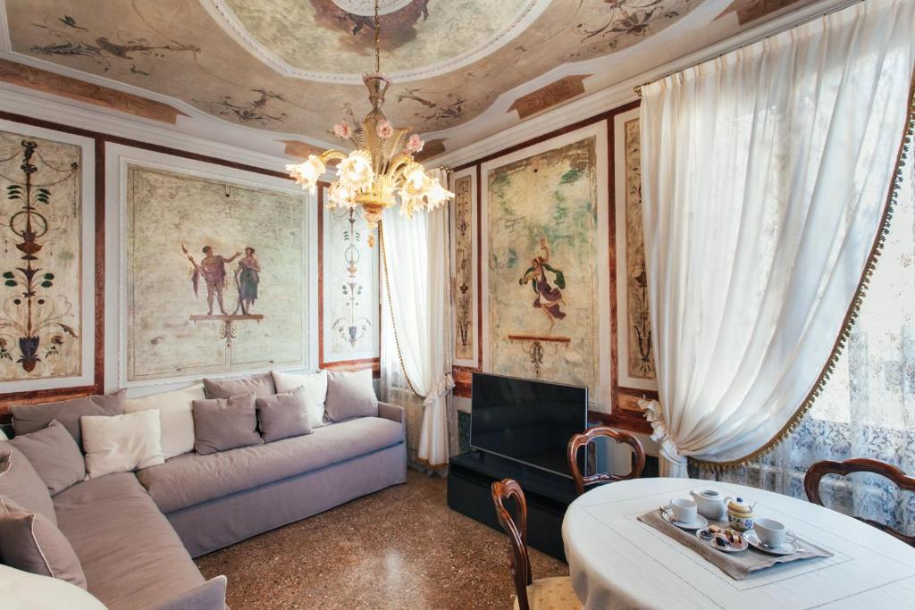 ヴェネツィアにあるResidenza Dei Dogiのソファ付きのリビングルーム、壁に絵画が飾られています。