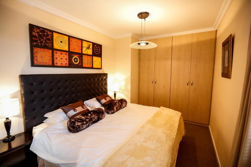 a bedroom with a bed with two pillows on it at Secret Garden Guesthouse in Bloubergstrand