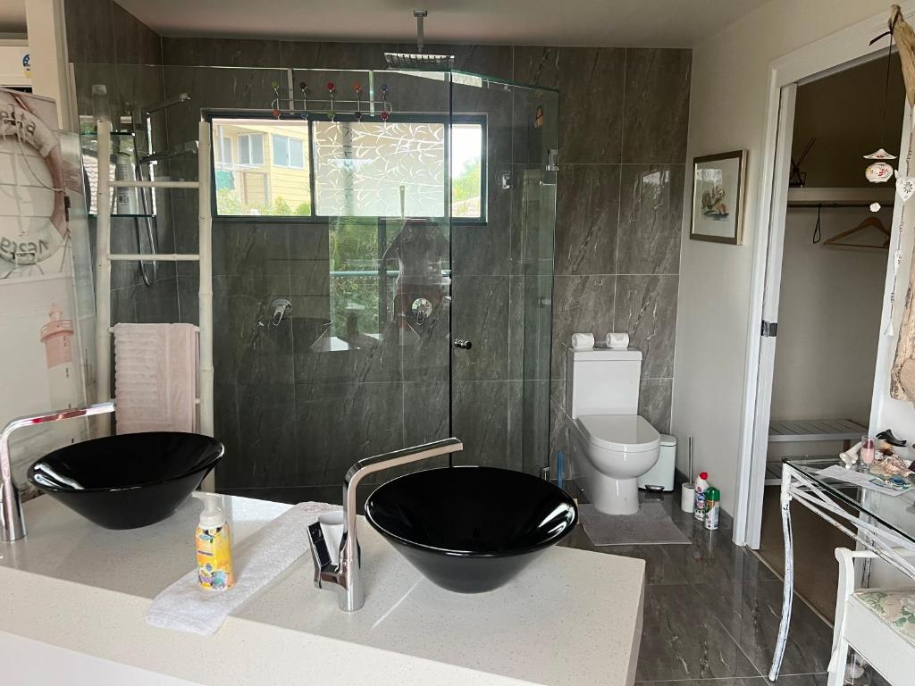 un bagno con 2 lavandini neri e una doccia di Gina‘s Place a Peregian Beach