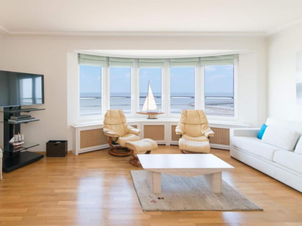 a living room with a white couch and chairs and the ocean at Studio in Ostend with Stunning Sea Views in Ostend