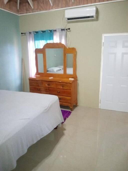 a bedroom with a dresser with a mirror and a bed at Dunbar's Two bedroom in Montego Bay