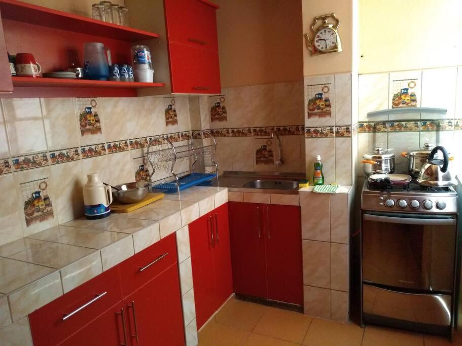 a small kitchen with red cabinets and a stove at Departamento ORILLAS DEL LAGO in Puno