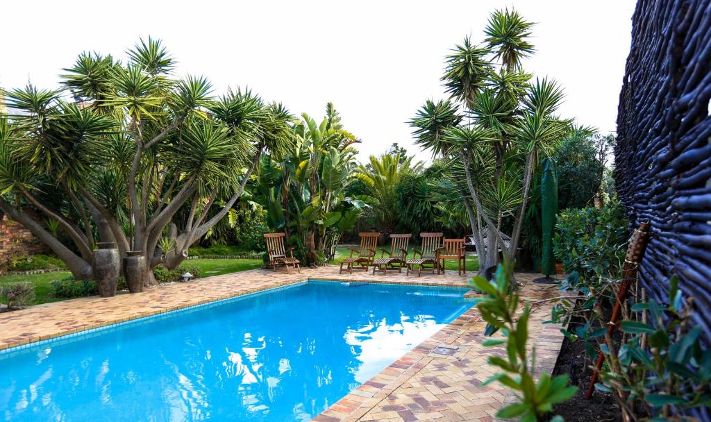 a swimming pool in a yard with palm trees at Secret Garden Guesthouse in Bloubergstrand
