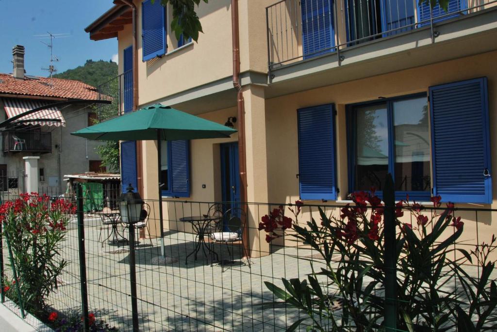 un patio con una sombrilla verde frente a una casa en B&B La Casa di Trizzi, en Como