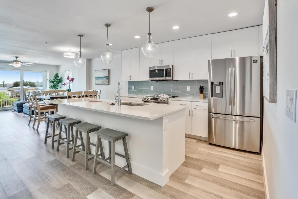 a kitchen with white cabinets and a large island with bar stools at Madeira Del Mar 305 in St Pete Beach