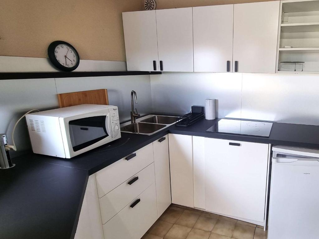 une cuisine avec un micro-ondes et un évier dans l'établissement Charmant T2 climatisé avec piscine et parking à 100m de la mer - FR-1-607-207, au Cap d'Agde