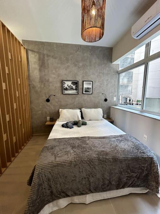 une chambre avec un grand lit et une grande fenêtre dans l'établissement Moderno Loft - Centro Rio de Janeiro, à Rio de Janeiro