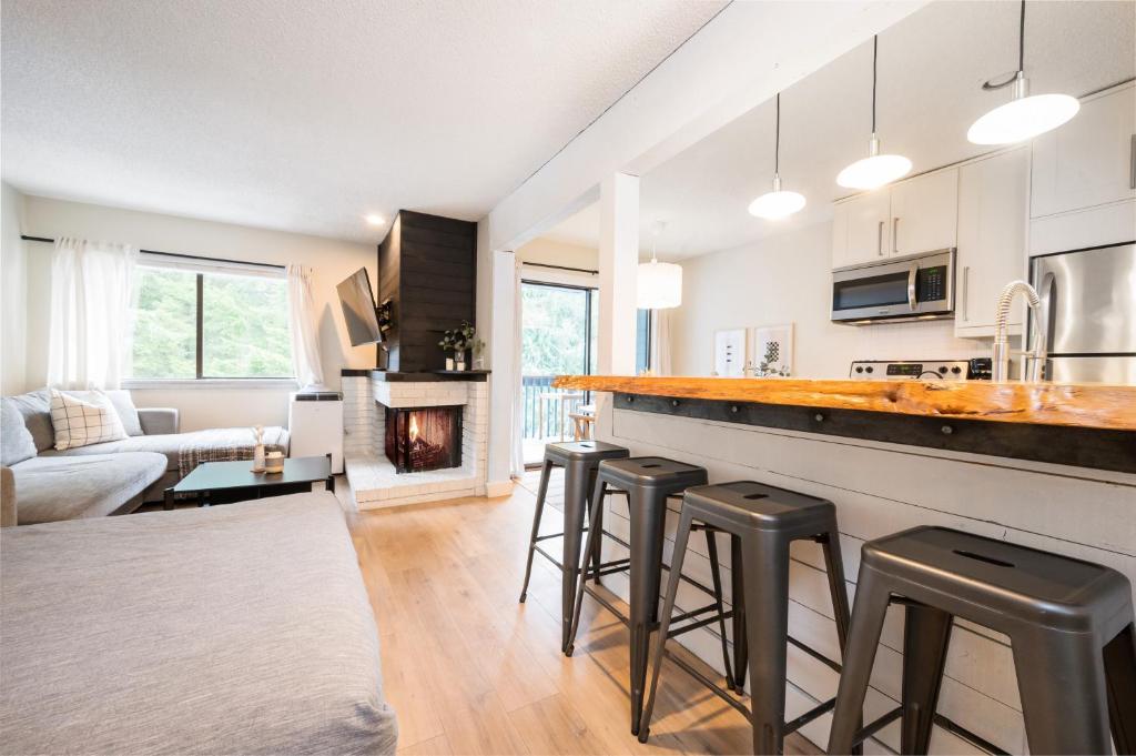 a kitchen and living room with a counter and stools at Creekside Oasis 4 Beds Pool and Hot Tub in Whistler