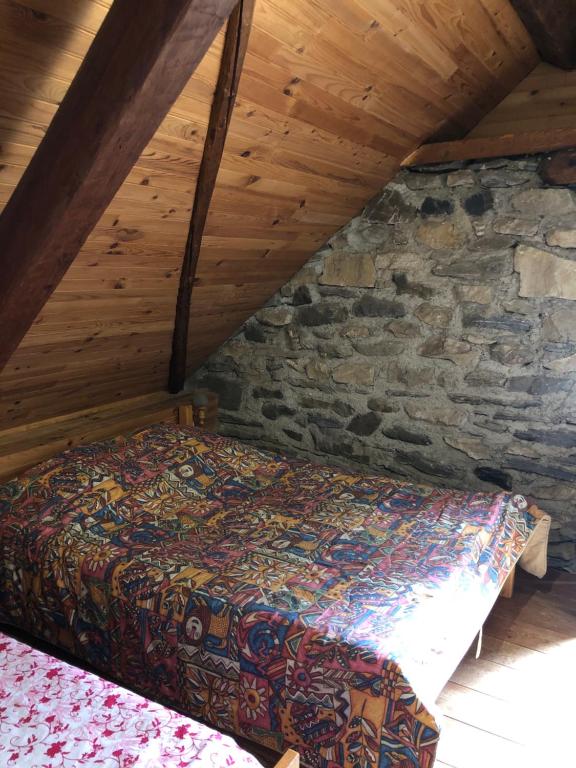 a bed in a attic with a stone wall at Bergerie authentique au cœur des Pyrénées in Eaux-Bonnes