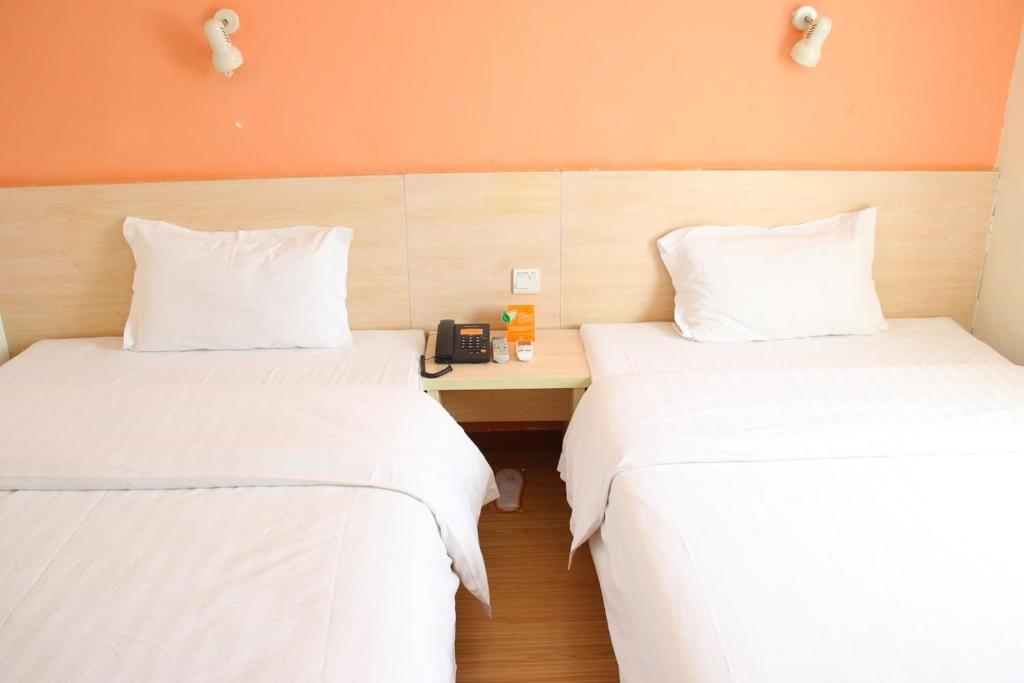 Habitación con 2 camas con sábanas blancas y escritorio. en 7Days Premium Nanchang Railway Station en Nanchang