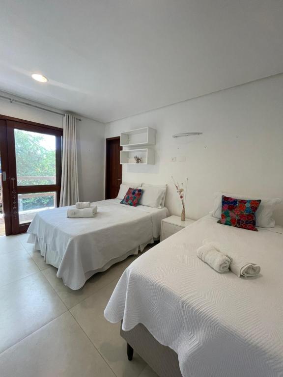 a bedroom with two beds and a window at Suites Amma Noronha in Fernando de Noronha