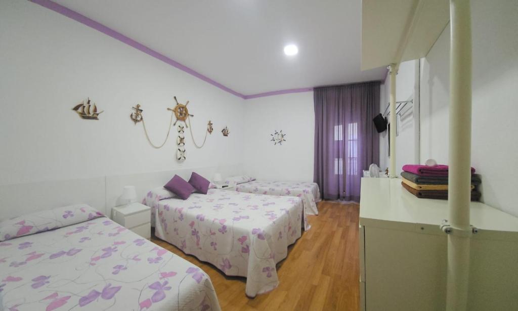 Un dormitorio con 2 camas y una mesa con barra. en Hostal Loyola, en Madrid