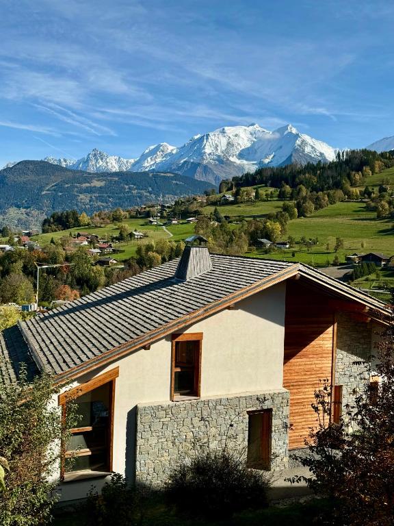 une maison avec des montagnes enneigées en arrière-plan dans l'établissement Chalet Petit Val, à Combloux