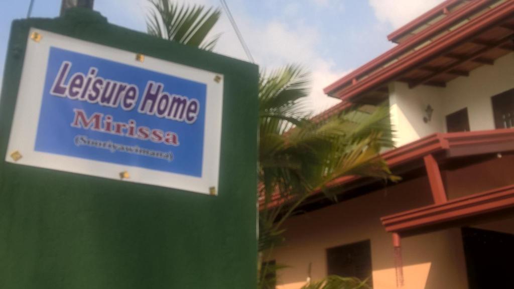 a sign for a house in front of a building at Leisure Home Mirissa in Mirissa