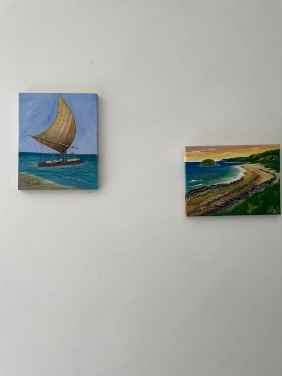 two paintings of a sail boat on the beach at Suites Amma Noronha in Fernando de Noronha