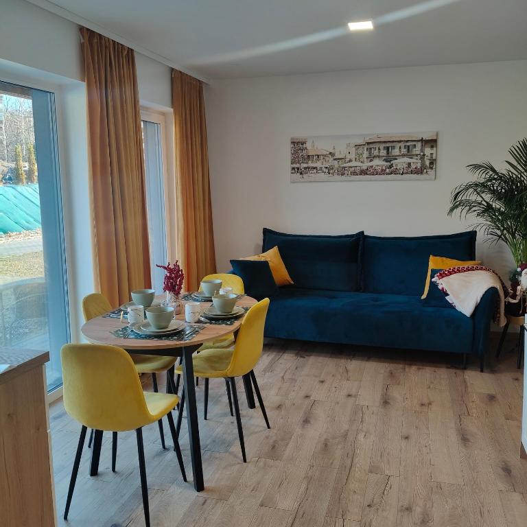 a living room with a blue couch and a table and chairs at Apartament ZłotogórSKI Lądek-Zdrój in Lądek-Zdrój