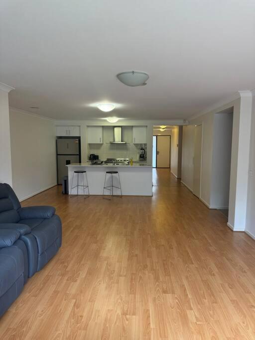 an empty living room with a blue couch and a kitchen at The Blissful Abode in Truganina