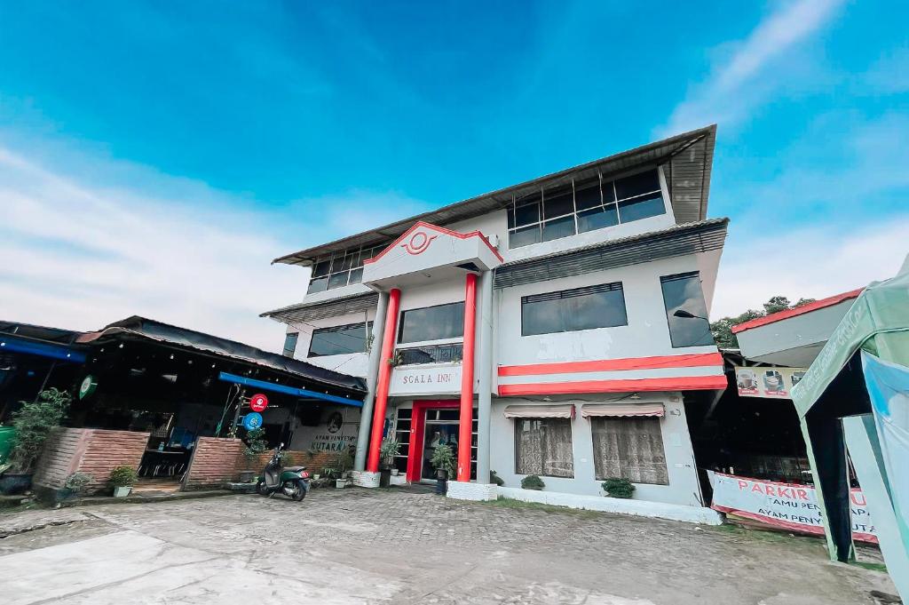 a white building with red trim on a street at Scala Inn By Helocus in Medan