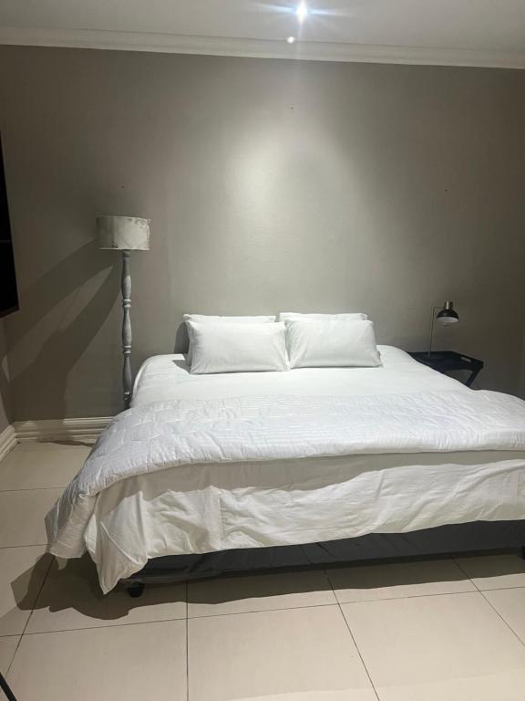 a bedroom with a large bed with white sheets and pillows at Luband Stelties in Nelspruit
