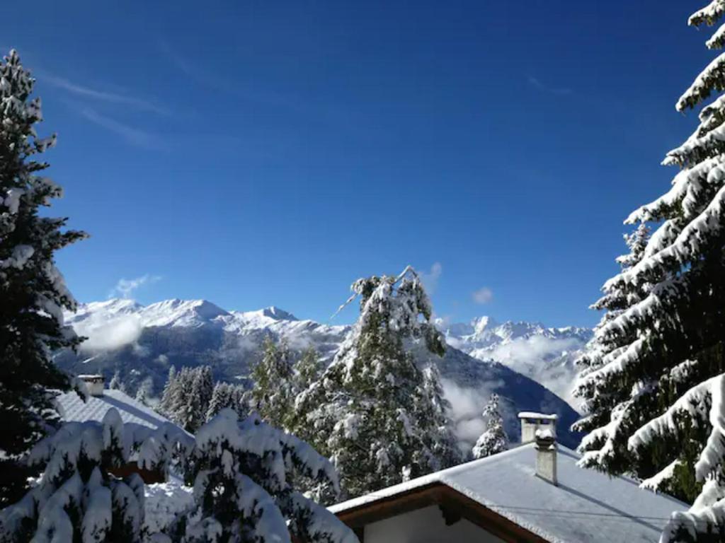 a snow covered mountain with trees and a house at Chalet Taipan Verbier in Verbier
