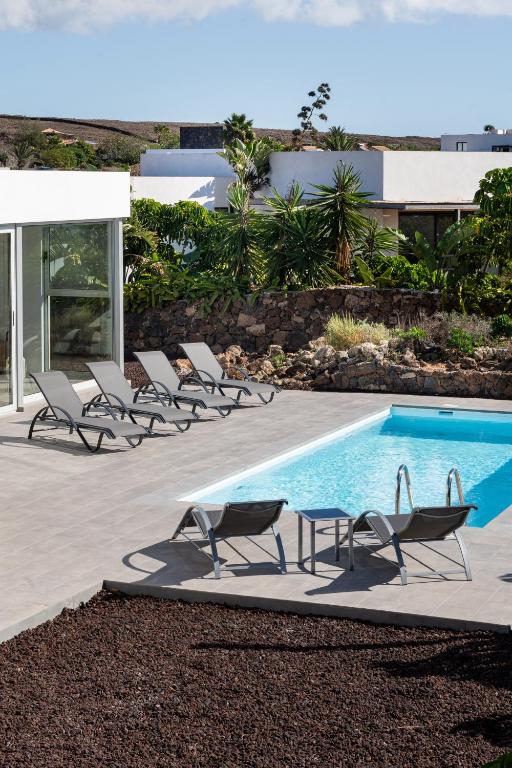 a group of chairs sitting next to a swimming pool at Almara House - Luxury Villa with Heated Pool in La Oliva