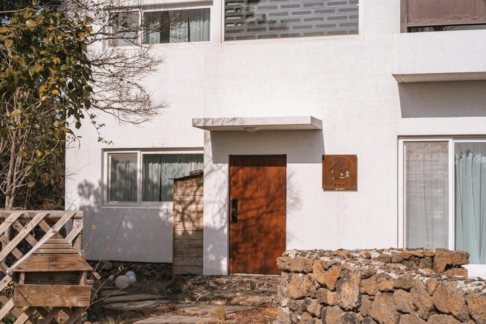 Un edificio blanco con una puerta de madera delante. en Jeju Stay Orot, en Jeju