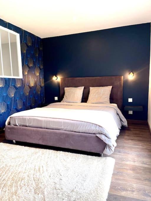 une chambre avec un grand lit avec un mur bleu dans l'établissement Le Cosy, à Saint-Martin-Lalande