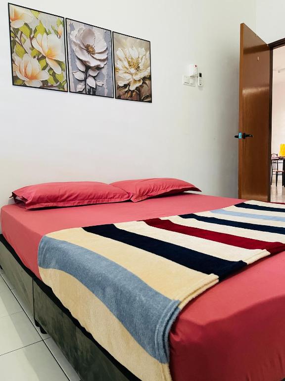 a bed with a colorful blanket on top of it at Al Ghazali Homestay in Seri Iskandar
