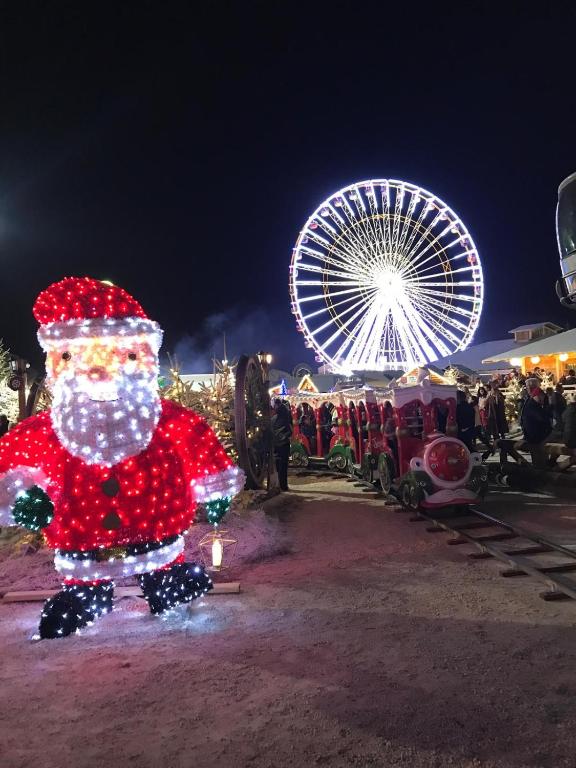 a santa claus display in front of a ferris wheel at Azur, a 100m du marché de Noel, appartement 4 personnes et parking privé in Le Barcarès