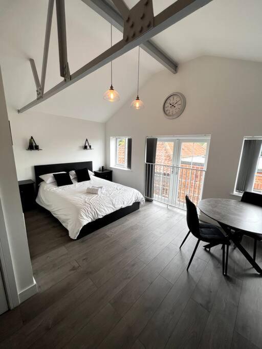 1 dormitorio con cama, mesa y reloj en Central Hedon modern apartment -, en Hedon